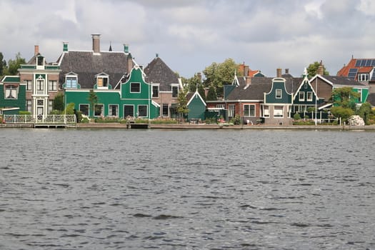 Typical Dutch houses on the canal near Amsterdam. In the land of windmills there are many traditional houses along the river.