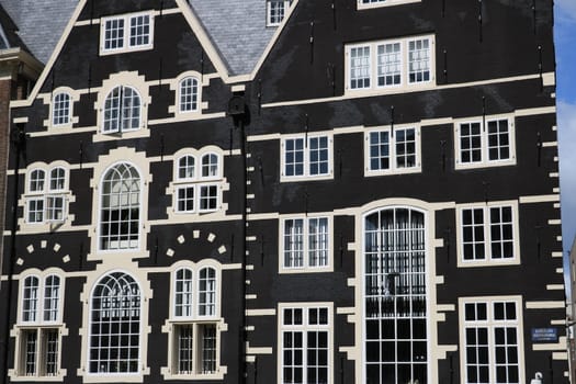 Amsterdam, Netherlands. About the July 2019. Typical Dutch houses seen from the canals of Amsterdam. Facade painted brown with white windows.