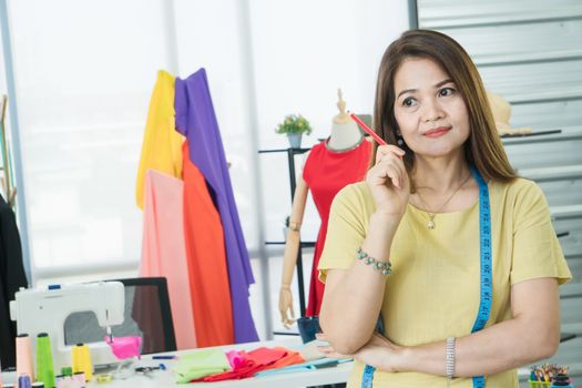 A senior female fashion designer from Asia is working in a textile factory. Confidently with starting a new business And smile at the camera friendly