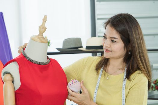 A senior female fashion designer from Asia is working in a textile factory. Confidently with starting a new business