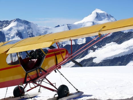 Jungfrau, Switzerland. A small yellow touring plane with red decorations on the snow of the Swiss mountains.