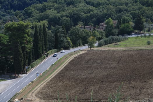 Road with cars on the Chianti hills. Cultivated fields and farmhouses in the Tuscan countryside near Florence. Greve in Chianti.