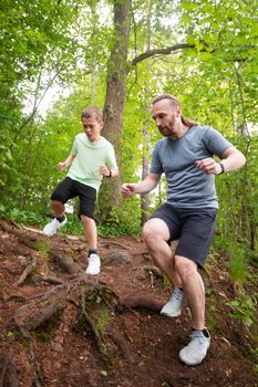 Father and son run in forest together, care, sport, parenting, healthy lifestyle concept
