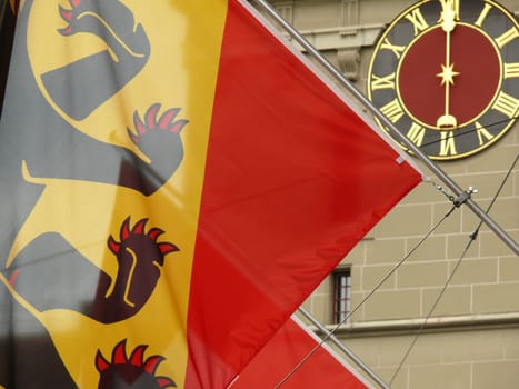 The flag with the bear of Bern and in the background the clock face of an original watch with a single hand.