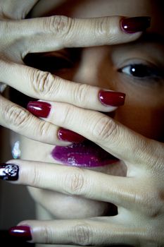 Portrait of woman with hand over face. Red makeup lips and nails