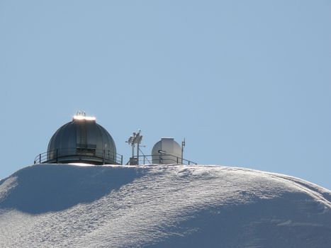 The domes of the observatory resumed from a point of view that makes them appear half-submerged by the snow