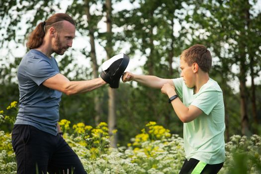 Father and son training to box in the park outdoors, fighting, care, sport, parenting, healthy lifestyle concept
