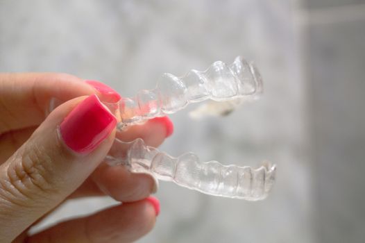 Invisible dental retainer held by womans hand. Copy space