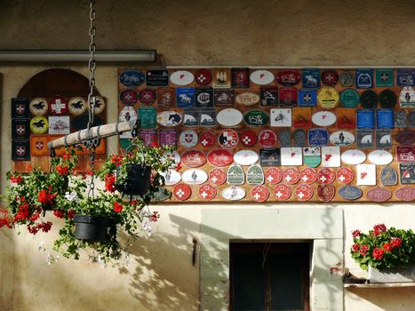 Under a porch a collection of plaques for participation in horse races and red flower vases.