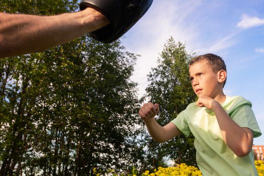 Father and son training to box in the park outdoors, fighting, care, sport, parenting, healthy lifestyle concept