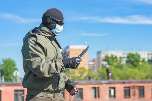 Armed man with a knife in a balaclava, black glasses and a medical mask in profile