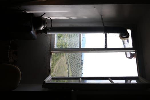 Old artist's studio window with the backdrop of the hills of Florence. In the foreground a charcoal stove with kettle placed on top.