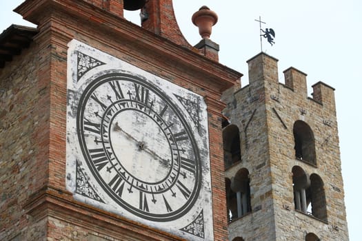 Towers with bell tower and large clock at the church of Impruneta, near Florence. Bell towers in terracotta and stone bricks.