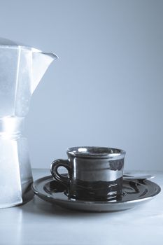 Cup of coffee next to classic Italian coffee maker