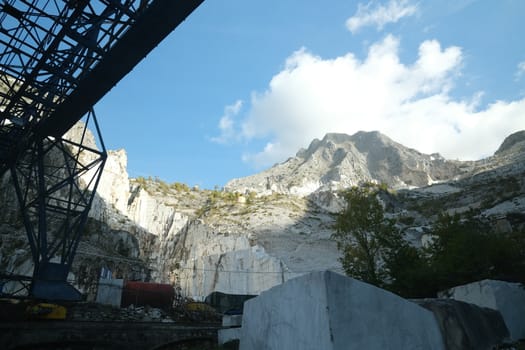 Panoramic view of the Apuan Alps from a quarry of white Carrara marble. A large overhead crane used to move marble blocks.