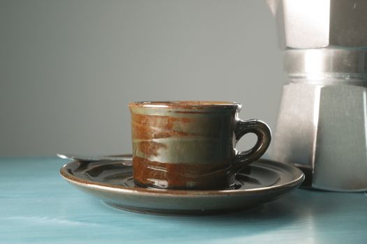 Cup of coffee next to classic Italian coffee maker
