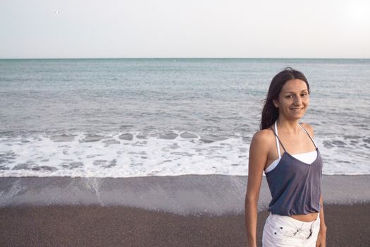 Mujer joven en la playa en actitud muy positiva y feliz. Precioso atardecer