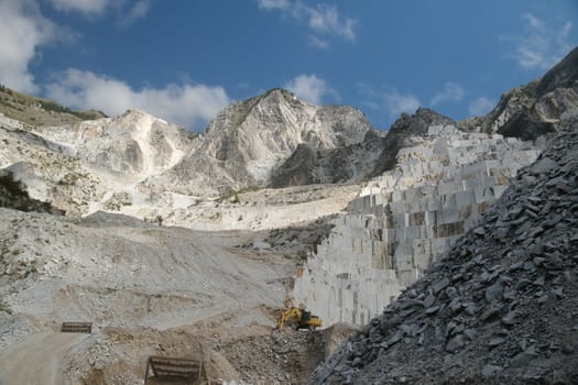 Carrara, Tuscany, Italy. About 09/2019. Panorama of a white Carrara marble quarry in Tuscany. Mountains of the Apuan Alps, blue sky and cloud.