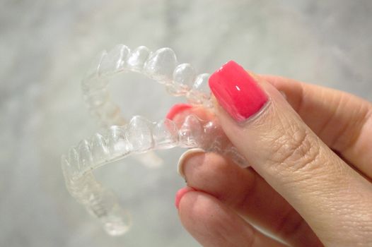 Invisible dental retainer held by womans hand. Copy space