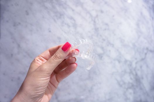 Invisible dental retainer held by womans hand. Copy space