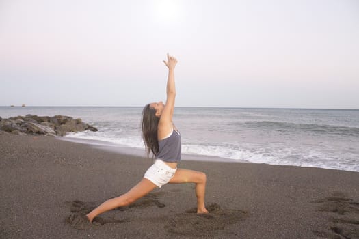 Young athlete woman practicing yoga on the beach. Beautiful sunset on the beach