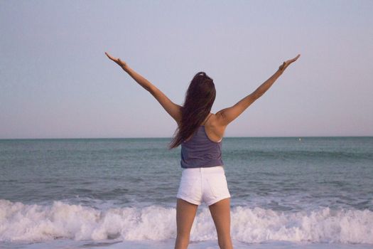 Mujer joven en la playa en actitud muy positiva y feliz. Precioso atardecer