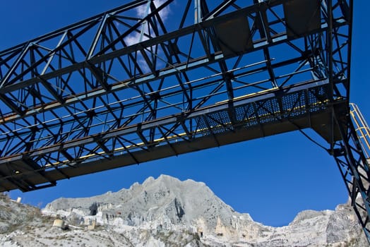 In a marble deposit on the Carrara mountains, an overhead crane is used to move the white marble blocks.