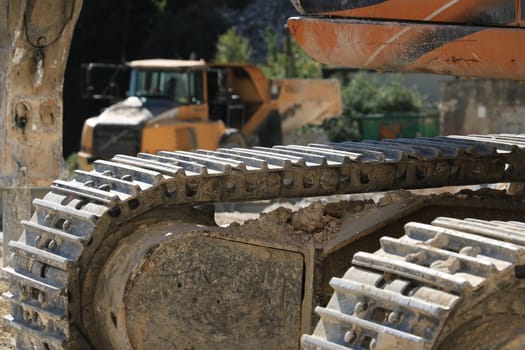 Carrara, Italy. A dumper truck used in a Carrara marble quarry. Large yellow dump truck with body. In the foreground the tracks of an excavator.