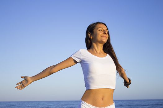 Woman dressed in white barefoot on the beach sand. Smiling