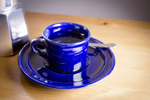 Cup of coffee next to classic Italian coffee maker