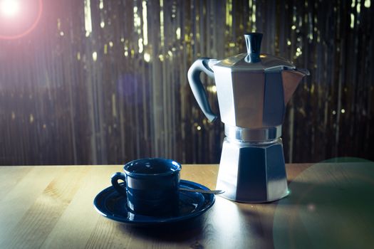 Cup of coffee next to classic Italian coffee maker