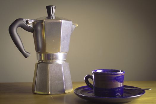 Cup of coffee next to classic Italian coffee maker