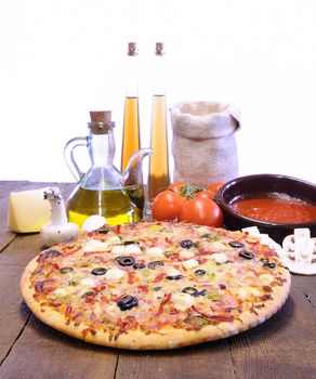 Pizza and ingredients on the kitchen table.