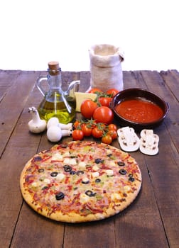 Pizza and ingredients on the kitchen table.