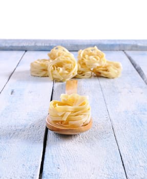 Tagliatelle in a spoon on the kitchen table.