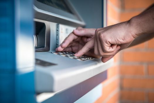 Entering a credit card pin on an ATM keyboard.