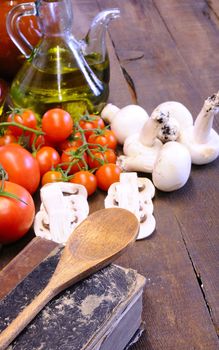 Cookbook over the kitchen table with vegetables.