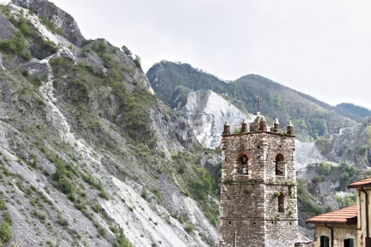 Colonnata, Carrara, Tuscany, Italy. Bell tower of the church built with white marble pebbles. The ancient village, famous for its lard, is located in the heart of the Carrara marble quarries. 
  