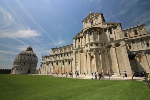 Pisa, Tuscany, Italy. 06/21/2019. Piazza dei miracoli of Pisa. Cathedral and baptistery. Many tourists admire the beauty of the Tuscan city. Blue sky.