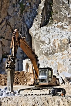 Carrara, Italy. Excavator with demolition hammer in a Carrara marble quarry. A large excavator shovel in a quarry in the Apuan Alps mountains.