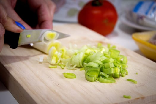 Sliced leek on a wooden cutting board. No people