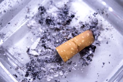 Cigarette consumed in an ashtray with ashes. No people
