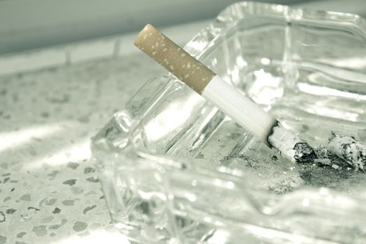 Lighted cigarette supported on ashtray. No people