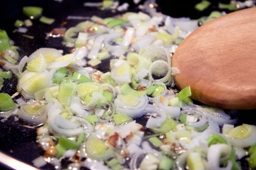 Onion stir fry with leek in frying pan. No people