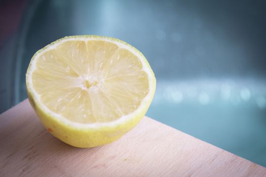 Half lemon cut on wooden cutting board. No people