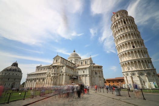 Pisa, Tuscany, Italy. 06/21/2019.  Piazza dei miracoli of Pisa. Travelers admire architecture. Cathedral, leaning tower of the Tuscan city. Blue sky with clouds.