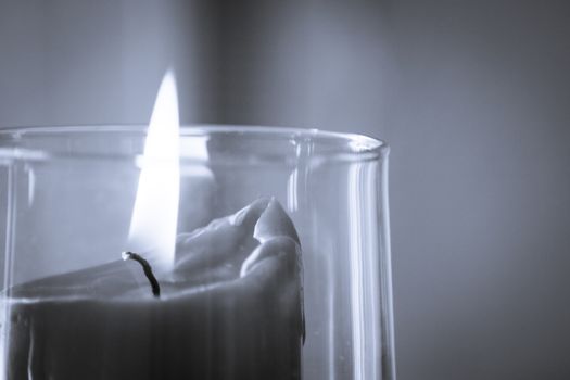 Burning red candle inside a clear glass vase. No people