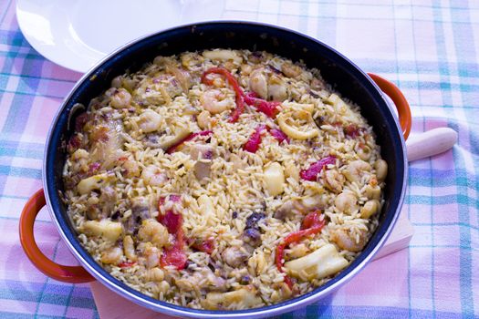 Rice paella cooked with chicken, seafood and vegetables. No people