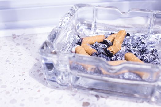 Ashtray with several cigarettes consumed and extinguished. Cigarette ash