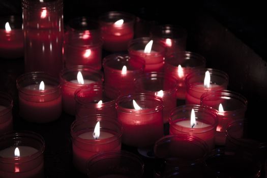 Many burning candles with red plastic sheath. No people